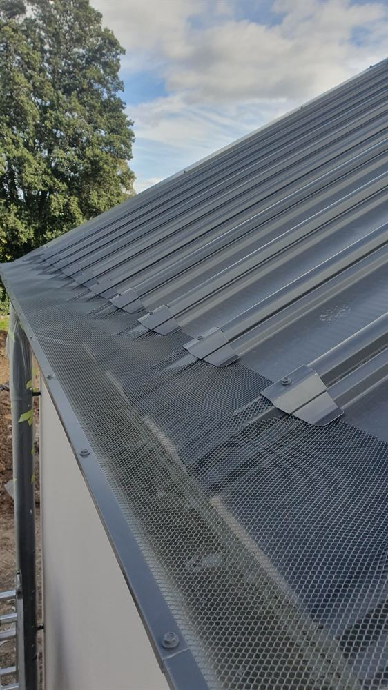 Gutter guard fitted along the edge of a Klip-lok roof