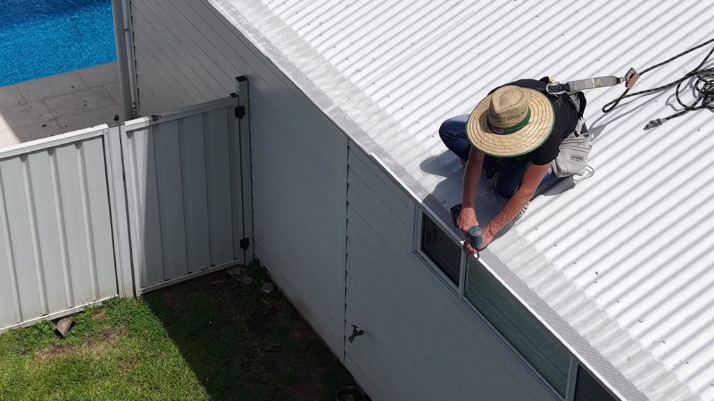 Gutter guard being fixed to the roof edge during installation in Warilla