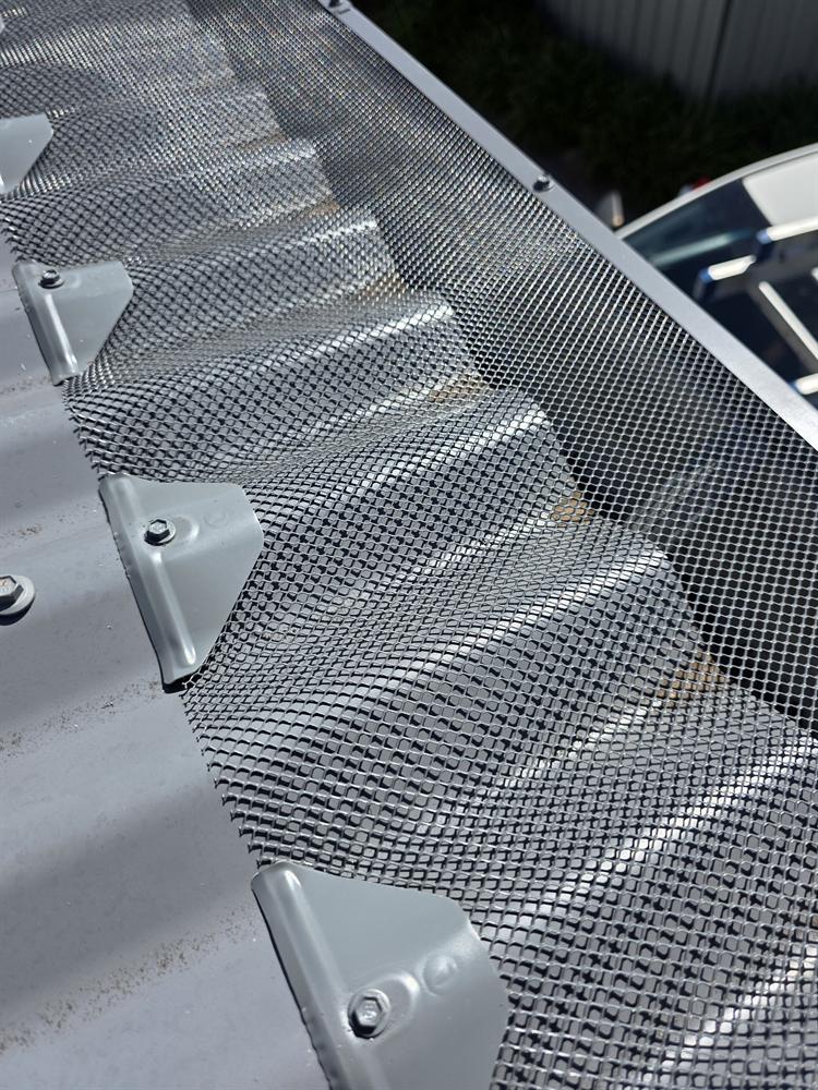 Gutter guard mesh and saddles fitted to a grey corrugated roof
