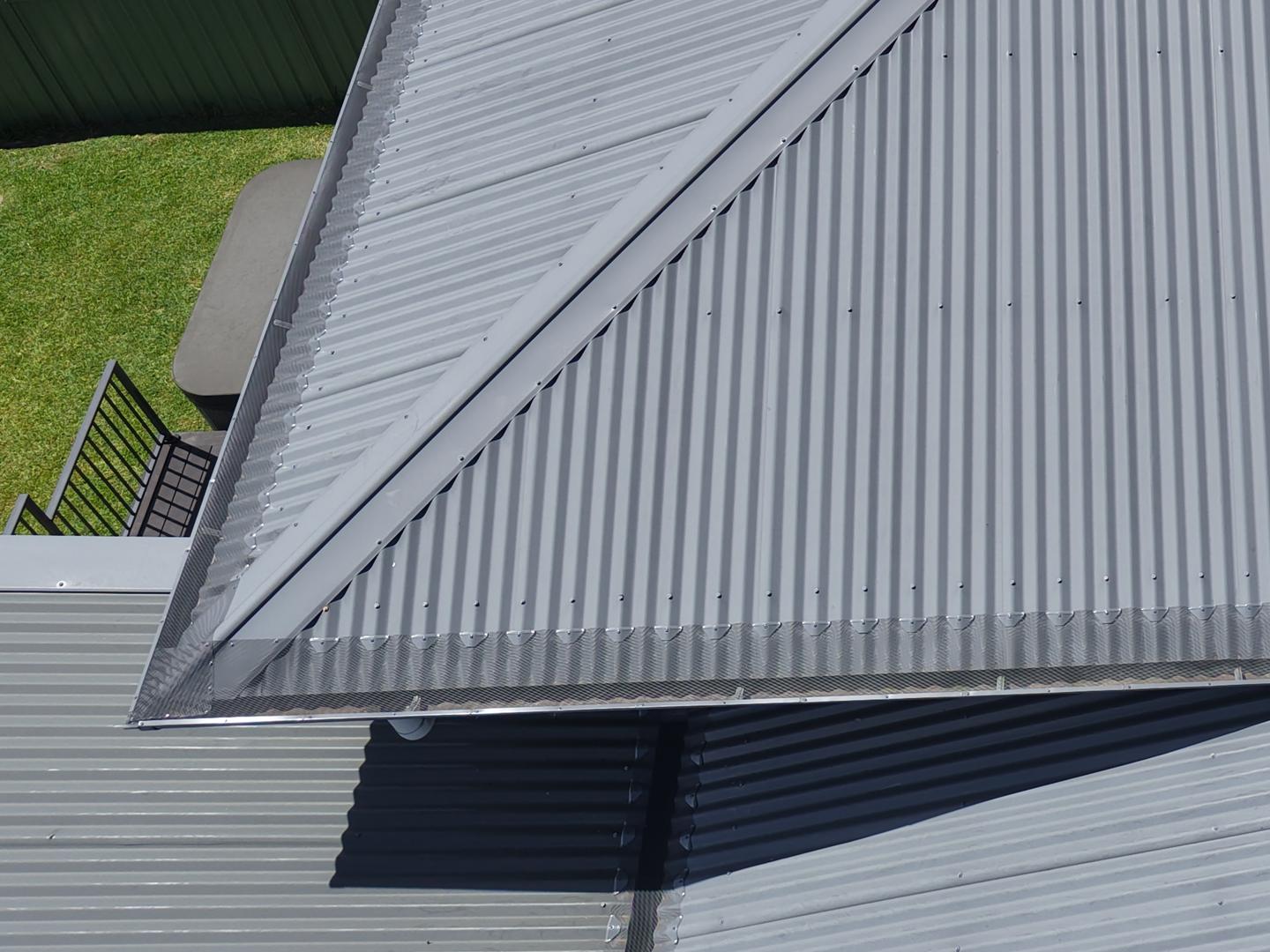 Drone close-up of aluminium mesh gutter guard along a grey Colorbond roof