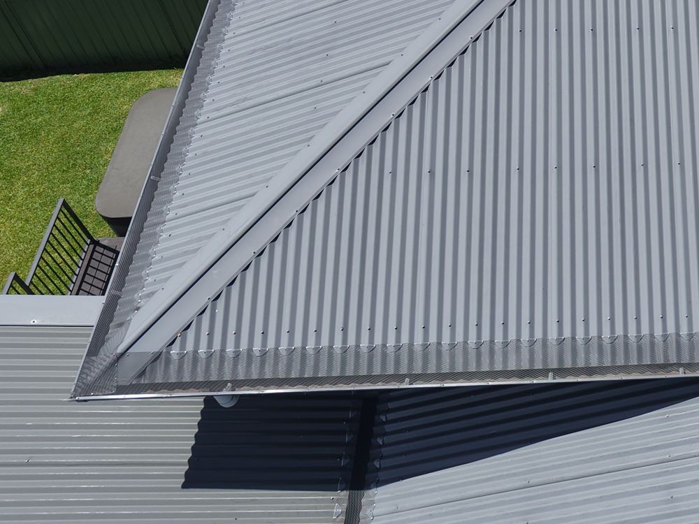 Drone close-up of aluminium mesh gutter guard along a grey Colorbond roof in Figtree